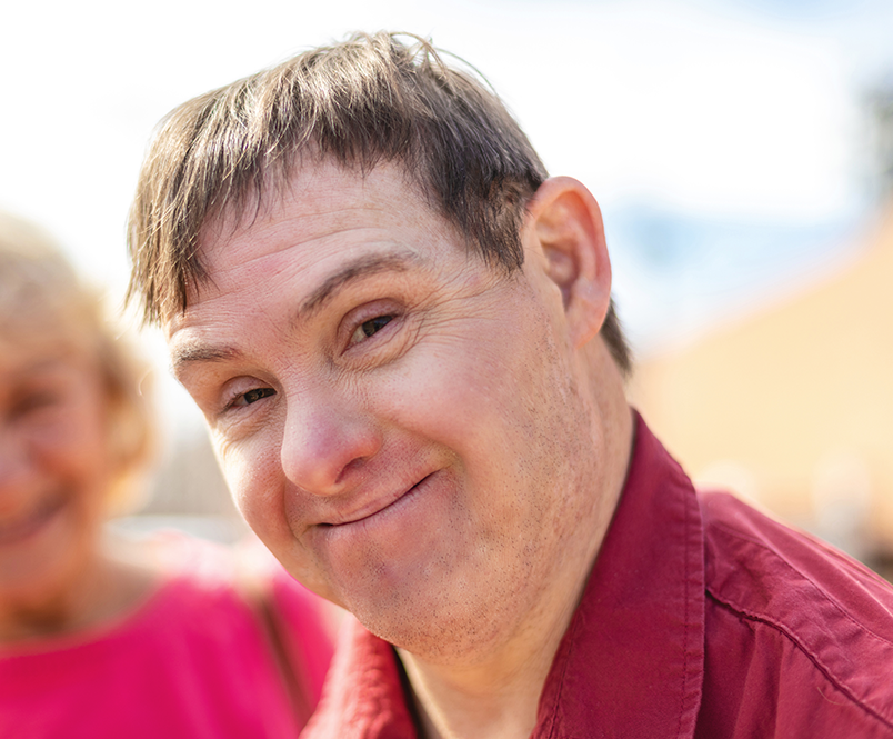 A disabled adult smiling at the camera.
