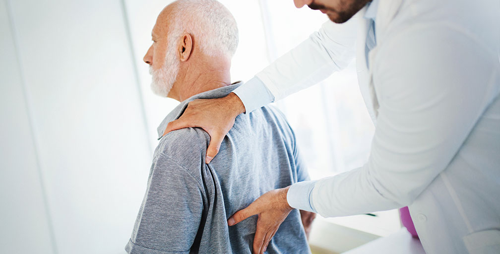 An older man being assessed for back pain.
